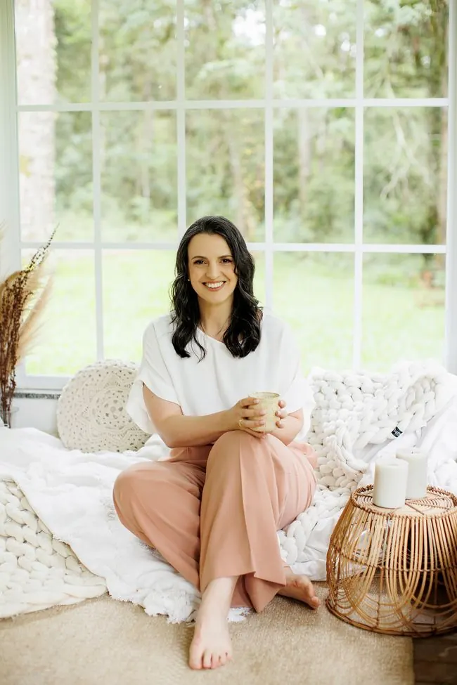 Juliane Marafon sentada no sofá do consultório, sorrindo